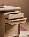 Wooden drawer unit with two open drawers on a neutral background